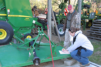 A volunteer helps a farmer with tractor safety